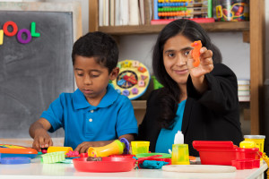 Hispanic Mom with Child in Home School Setting Showing Craft