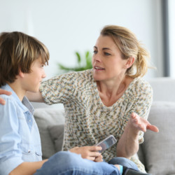 Mother giving warning to young boy using smartphone